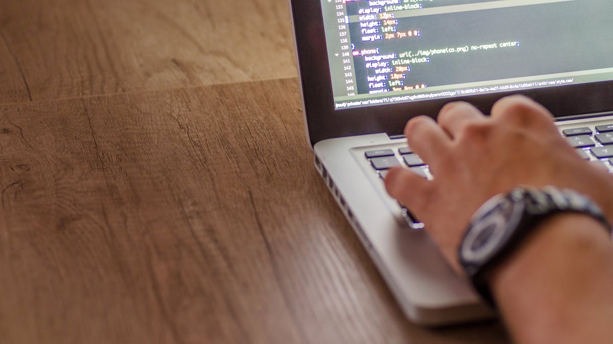 A developer writing code on a laptop