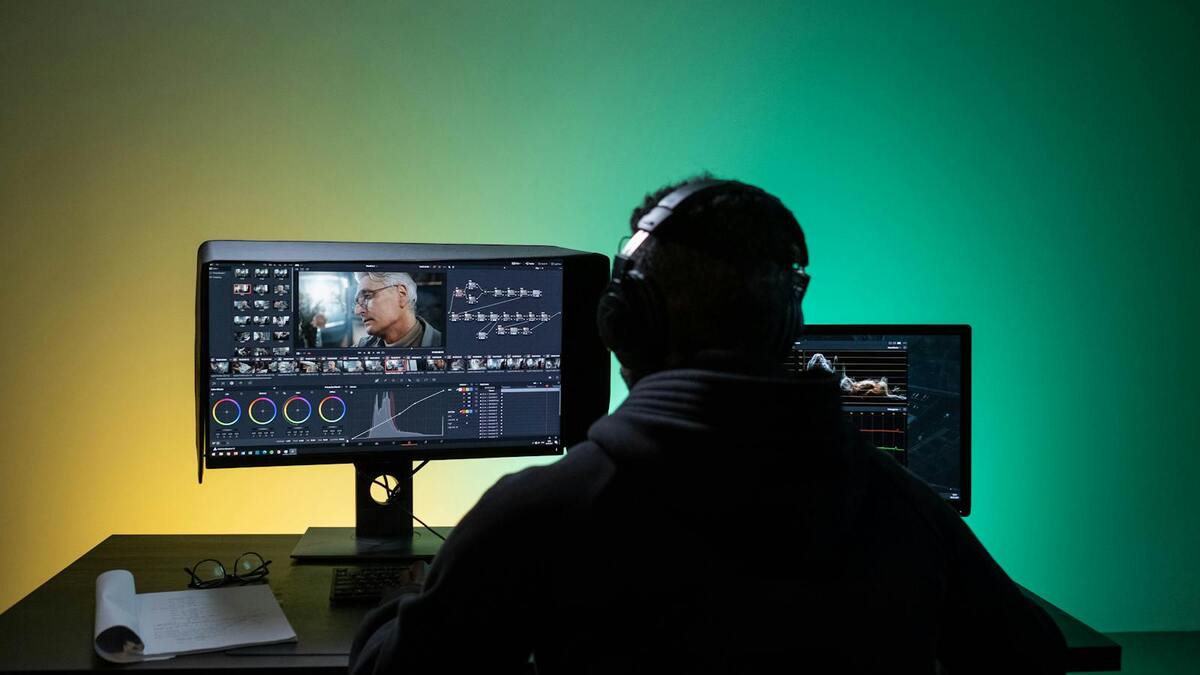Video editor working at dual monitors with color grading software