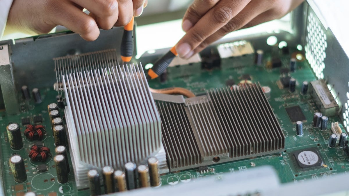 An engineer working on hardware components on a green circuit board with heatsinks