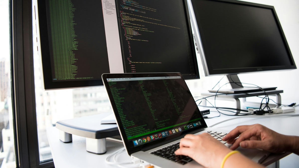 A developer coding at a laptop in a bright workspace