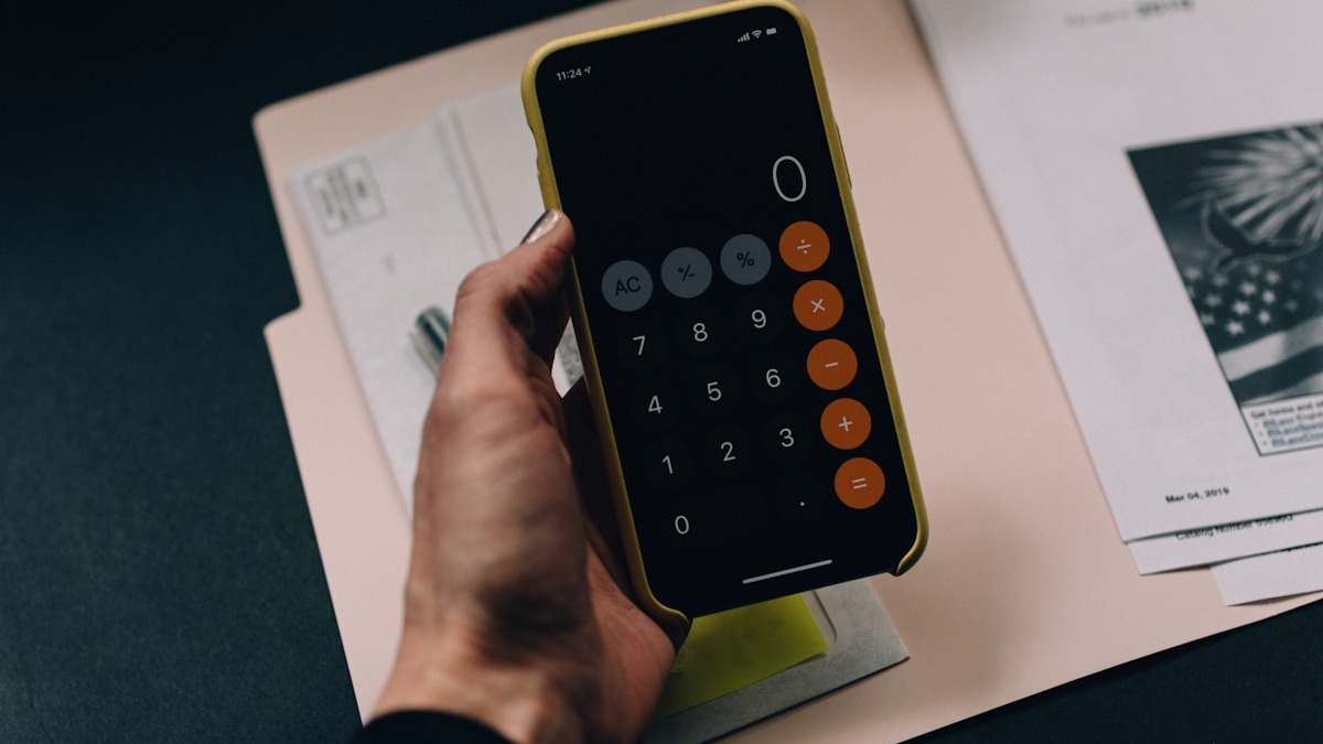 A calculator and pen on a notebook, representing the cost math behind API pricing decisions